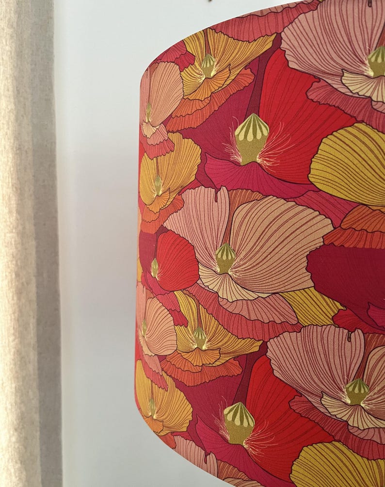 K&ouml;nnte beinhalten: Ein Lampenschirm mit einem auff&auml;lligen Blumenmuster. Das Design zeigt gro&szlig;e, stilisierte Blumen in Rot-, Orange- und Gelbt&ouml;nen vor einem tiefroten Hintergrund. Die Blumen haben detaillierte Bl&uuml;tenblattlinien und gr&uuml;ne Akzente.