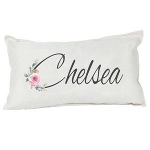 May include: A white pillow with a floral design and the name "Chelsea" printed in black cursive script.