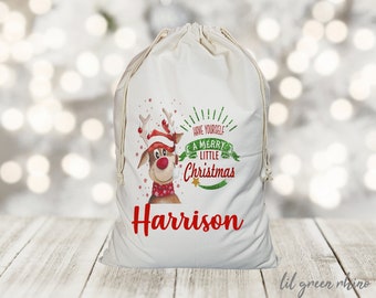 May include: White canvas gift bag with a red and green reindeer design. The bag has the text "Have Yourself a Merry Little Christmas" and the name "Harrison" printed on it.