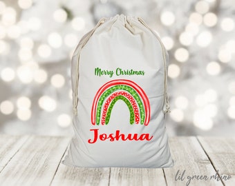 May include: White canvas Christmas gift bag with a red and green rainbow design and the text "Merry Christmas Joshua".