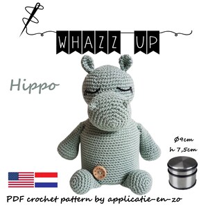 May include: A crocheted hippo in a soft green color, with closed eyes and a button detail. The text "WHAZZ UP" is displayed above the hippo. The hippo is approximately 3.5 inches tall. A PDF crochet pattern is available.