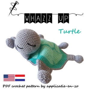 Puede incluir: Un juguete de amigurumi de ganchillo en forma de tortuga con un cuerpo gris y un caparazón turquesa. El juguete está acostado de lado con la cabeza apoyada en el caparazón. El juguete está etiquetado como "Whazz Up Turtle" y es un patrón de ganchillo PDF de applicatie-en-zo.