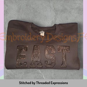 May include: A brown sweatshirt with the word "EAST" embroidered in black glitter on the front.