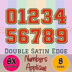 May include: A set of iron-on numbers in red with a gold border and black outline. The numbers 0 through 9 are displayed. The text "DOUBLE SATIN EDGE" and "Numbers Applique" are also shown.