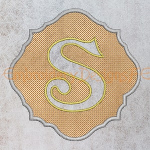May include: A yellow embroidered letter "S" in a decorative, scalloped frame. The frame is a light gray color and the background is a light orange.