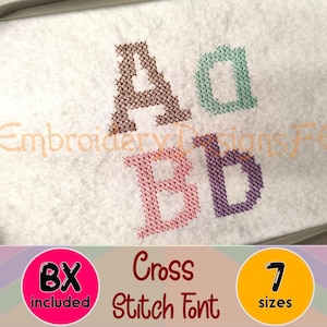 May include: An embroidery hoop containing white fabric with cross-stitch embroidery of the letters A, a, B, and b in brown, teal, pink, and purple. The image includes text reading EmbroideryDesignsFE, BX included, Cross Stitch Font, and 7 sizes.