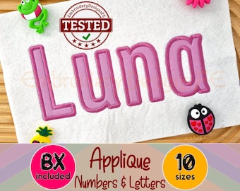 May include: A white fabric with the name "Luna" embroidered in pink, surrounded by decorative elements. The image includes a frog, a pineapple, and a ladybug-shaped embellishment. Text on the image includes "Tested", "BX included", "Applique Numbers & Letters", and "10 sizes".
