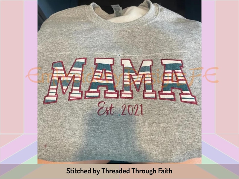 May include: Grey sweatshirt with the word "MAMA" in large, colourful, striped letters. The letters are outlined in maroon. Below the word "MAMA" is the text "Est. 2021" in maroon. The sweatshirt is stitched by "Threaded Through Faith".