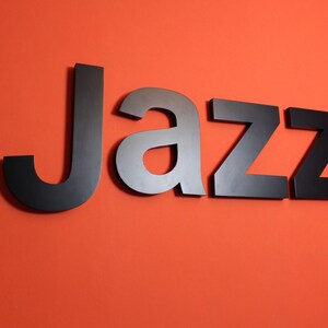 Letras de madera: gran palabra de jazz lacada en negro.