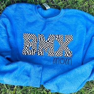 Könnte beinhalten: Ein königsblauer Pullover mit einem karierten "BMX mom"-Motiv.