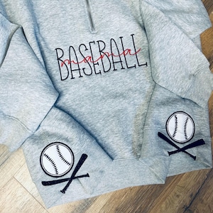 May include: Gray sweatshirt with the text "Baseball Mama Baseball" embroidered on the front. The sleeves have a baseball and crossed bats design embroidered on them.