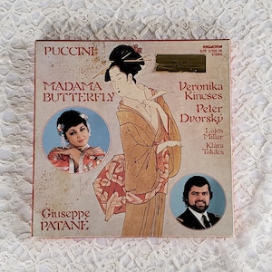 May include: A vintage record album cover featuring a colorful illustration of a woman in a traditional Japanese kimono. The album is titled "Madama Butterfly" by Puccini, with the names of the performers Veronika Kincses, Peter Dvorský, Lajos Miller, and Klára Takács listed below.