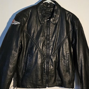 May include: Black leather motorcycle jacket with a Harley Davidson logo patch on the left sleeve. The jacket has a zipper closure and a braided detail on the front.