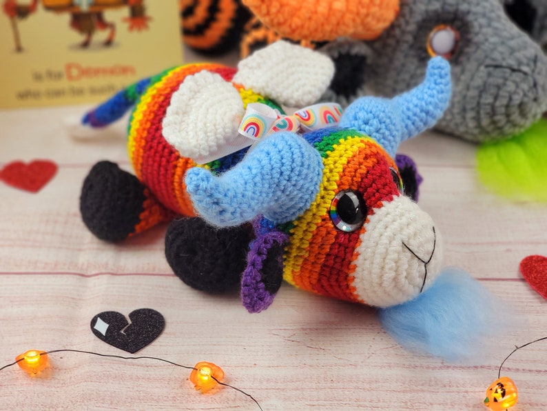Peut inclure: Un jouet de taureau crochet&eacute; &agrave; la main aux couleurs de l'arc-en-ciel. Le taureau a des cornes bleues, des oreilles blanches et des sabots noirs. Il a un museau blanc et de grands yeux brillants. Un petit ruban arc-en-ciel est nou&eacute; sur sa t&ecirc;te. Fait main.