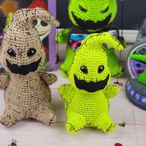 Puede incluir: Dos peluches de crochet del personaje Zero de Pesadilla antes de Navidad. Uno es beige con ojos negros y una boca negra, el otro es verde con ojos negros y una boca negra.