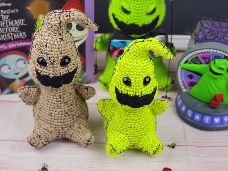 Puede incluir: Dos peluches de crochet del personaje Zero de Pesadilla antes de Navidad. Uno es beige con ojos negros y una boca negra, el otro es verde con ojos negros y una boca negra.