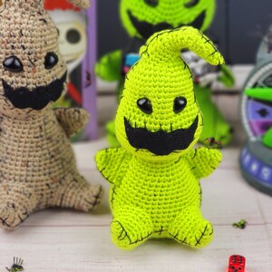 Puede incluir: Dos personajes de Pesadilla Antes de Navidad hechos a crochet. Uno es verde con una boca cosida negra y ojos negros. El otro es marr&oacute;n claro con una boca cosida negra y ojos negros.