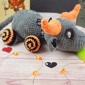 Peut inclure: Un dragon en crochet gris fait &agrave; la main avec des cornes et des accents orange, des roues noires et orange et une langue verte. Le dragon a une &eacute;tiquette de cr&acirc;ne et est d&eacute;cor&eacute; de lumi&egrave;res et de coeurs sur le th&egrave;me d'Halloween.