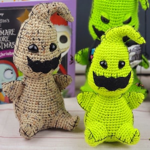 Puede incluir: Dos peluches de crochet del personaje 'Oogie Boogie' de la pel&iacute;cula 'Pesadilla antes de Navidad'. Uno es beige y el otro es verde. Ambos tienen ojos negros y un bigote negro.