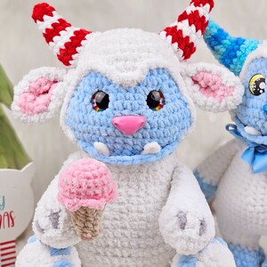 Pu&ograve; includere: Due giocattoli di peluche all'uncinetto, uno blu e bianco con un cono gelato rosa, l'altro bianco con accenti blu. Entrambi hanno occhi grandi e un'espressione amichevole.