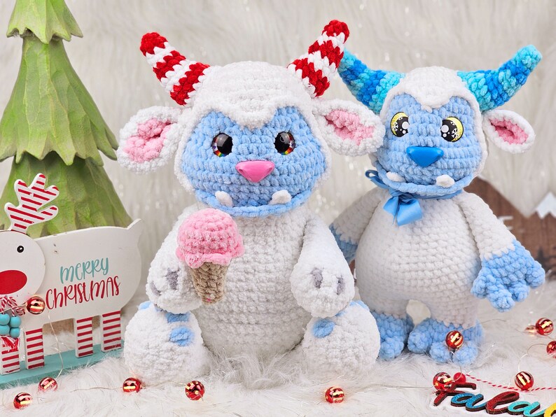 Pu&ograve; includere: Due peluche Yeti all'uncinetto, uno tiene un cono gelato rosa. Lo Yeti a sinistra ha corna a strisce rosso e bianco e pelliccia blu. Lo Yeti a destra ha corna a strisce blu e verdi e un fiocco blu.