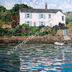 以下が含まれることがあります： 青いシャッターの付いた白い家が、緑の葉が生い茂る岩場の海岸に建っています。家は手前の波打つ水に映っています。この画像は紙の切れ端でできています。