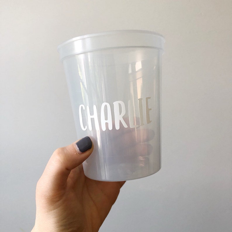 May include: A clear plastic cup with the name "Charlie" written on it in white lettering.