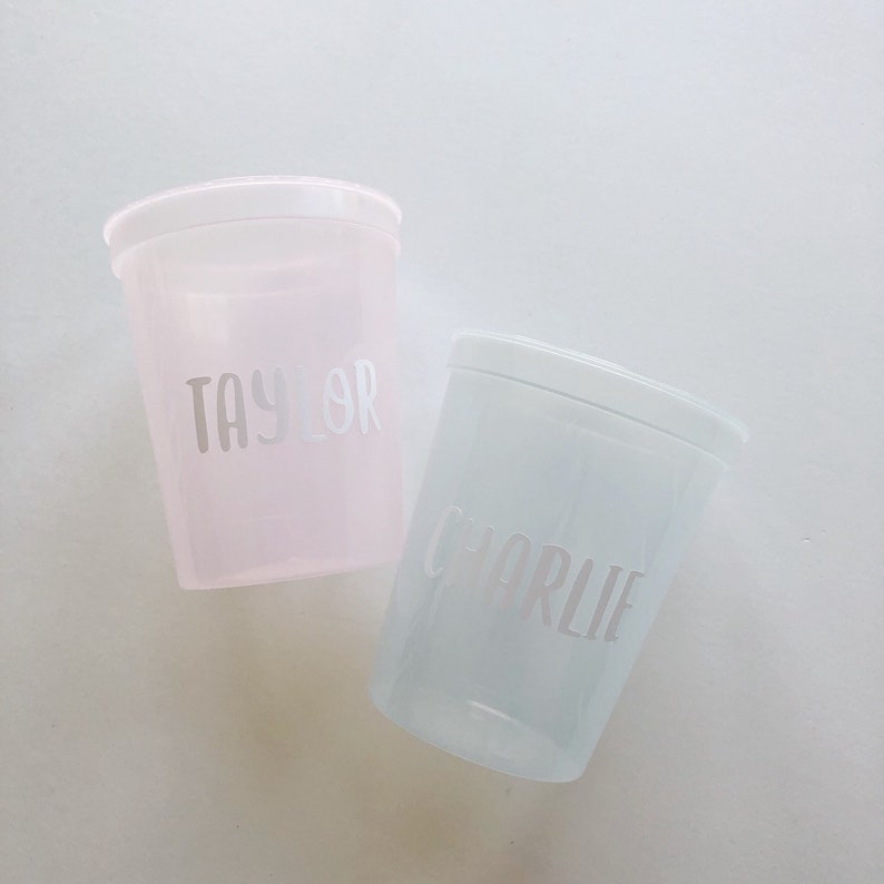 May include: Two clear plastic cups with personalised names. The pink cup says "Taylor" and the blue cup says "Charlie".