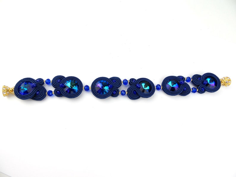 Peut inclure: Un bracelet bleu marine avec des cristaux bleus iris&eacute;s et des accents dor&eacute;s.