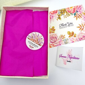 Peut inclure: Une bo&icirc;te cadeau blanche avec un papier de soie rose. La bo&icirc;te a un autocollant qui dit "Hand Made Just For You". La bo&icirc;te est &agrave; c&ocirc;t&eacute; d'une carte de remerciement avec un motif floral et le texte "Thank You Especially For You". Il y a aussi une carte de visite qui dit "Serena Napolitano Jewelry".