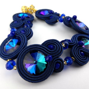 Peut inclure: Un bracelet bleu marine avec des cristaux bleus iris&eacute;s et des accents dor&eacute;s. Le bracelet est fait de cordon tress&eacute; et pr&eacute;sente un design unique et complexe.