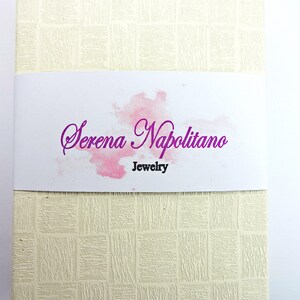 Peut inclure: Une bo&icirc;te blanche avec une surface textur&eacute;e et un motif aquarelle rose. Le texte "Serena Napolitano Jewelry" est imprim&eacute; en violet sur la bo&icirc;te.
