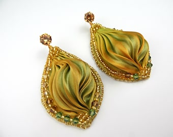 Op de afbeelding: Een paar groene en gouden zijden lint oorbellen met gouden en groene kralen accenten.