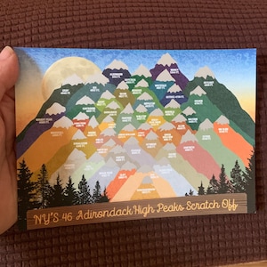 May include: A colorful scratch-off map featuring the 46 Adirondack High Peaks. The illustration depicts mountains in various colors with their elevations in feet. A full moon is in the background, and a forest is in the foreground.