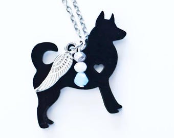 May include: A silver chain necklace with a black silhouette of a dog with a small silver wing charm and blue and white beads.