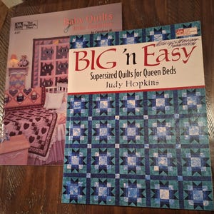 May include: Two quilting books are displayed. One is titled "Baby Quilts from Grandma" and the other is "BIG 'n Easy: Supersized Quilts for Queen Beds." The "BIG 'n Easy" book has a blue and green star pattern on the cover.