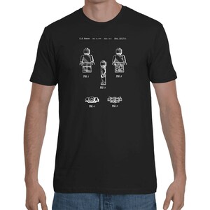 May include: Black t-shirt with a white print of a Lego figure patent design. The design includes five figures and the text "U.S. Patent: Dec. 23, 1977".