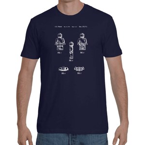 May include: A navy blue t-shirt with a white print of a Lego figure patent design. The design includes the text "U.S. Patent" and "Des. 253,711".
