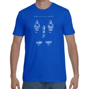 May include: A royal blue t-shirt with a white print of a Lego figure patent design. The patent number is U.S. Patent: Des. 233,711.