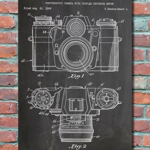 May include: Black and white line drawing of a photographic camera with coupled exposure meter patent, filed August 21, 1959, and issued May 15, 1962, patent number 3,034,411. The patent drawing shows two views of the camera, one from the top and one from the bottom.
