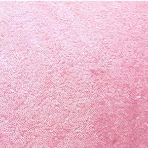 Puede incluir: Primer plano de una tela de lentejuelas rosas. Las lentejuelas, peque&ntilde;as y redondas, est&aacute;n densamente dispuestas, creando una superficie texturizada y brillante. El color es un rosa suave y claro, con ligeras variaciones de tono. El efecto general es de brillo y glamour.