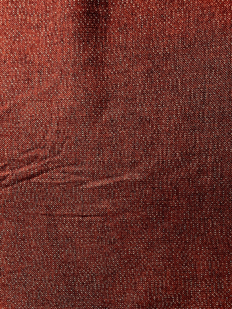 Pode incluir: Close-up de um tecido vermelho com um brilho sutil. O tecido tem uma apar&ecirc;ncia texturizada e tecida.
