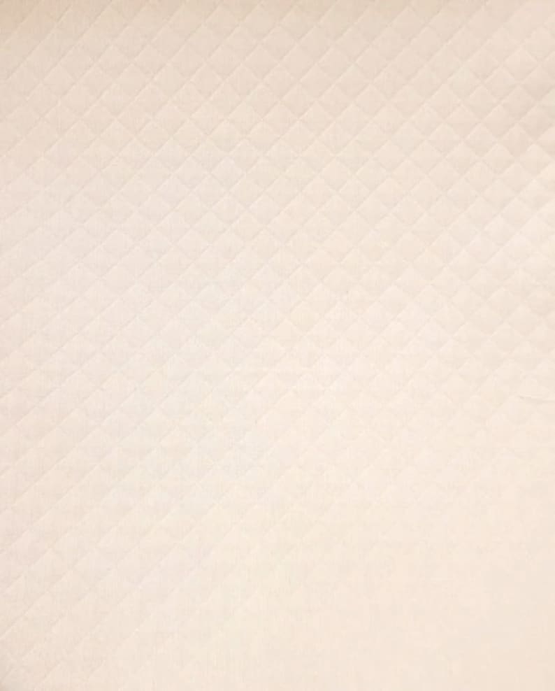 May include: A close-up of a white fabric with a subtle diamond pattern. The fabric has a smooth, slightly textured surface.