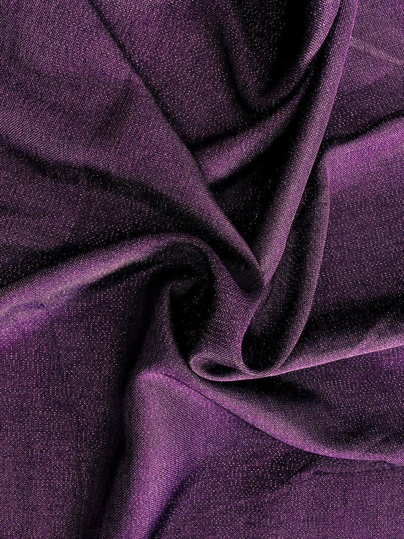 Pode incluir: Tecido roxo com um brilho sutil, drapeado e dobrado para mostrar a textura.