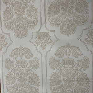 May include: Beige fabric with a repeating pattern of ornate floral designs. The pattern features a central motif of a vase with stylized flowers and leaves.