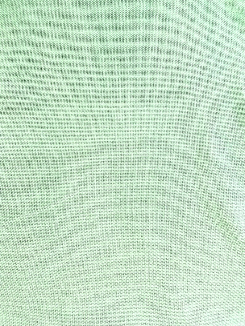 Pode incluir: Um close-up de um tecido verde claro com textura tecida.
