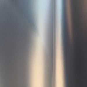 Könnte beinhalten: Nahaufnahme einer glatten, metallischen Oberfläche mit einem subtilen Farbverlauf von hellen zu dunklen Farbtönen. Die Oberfläche hat einen leichten Glanz, der einen reflektierenden Effekt erzeugt.
