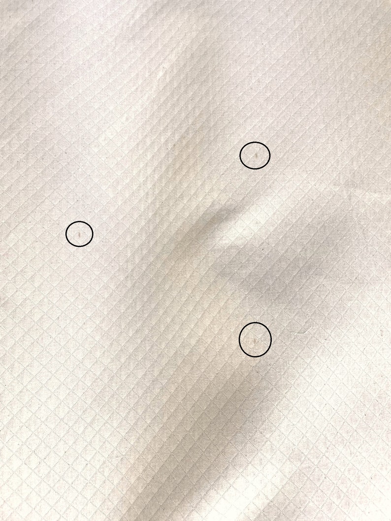 May include: Close-up of a white fabric with three small, circular holes.