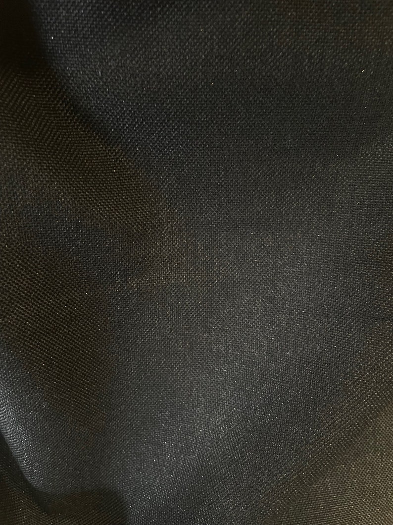 Pode incluir: Tecido preto com trama texturizada. O tecido tem um brilho sutil.