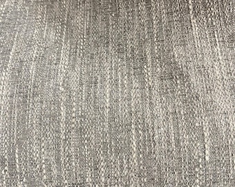 May include: Close-up of a textured fabric in shades of gray and white. The weave has a vertical pattern with subtle variations in color and texture, creating a visual depth. The fabric appears to be a blend of materials.